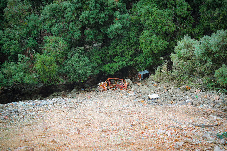 Aussicht in einen Abhang mit einem alten Unfallwagen