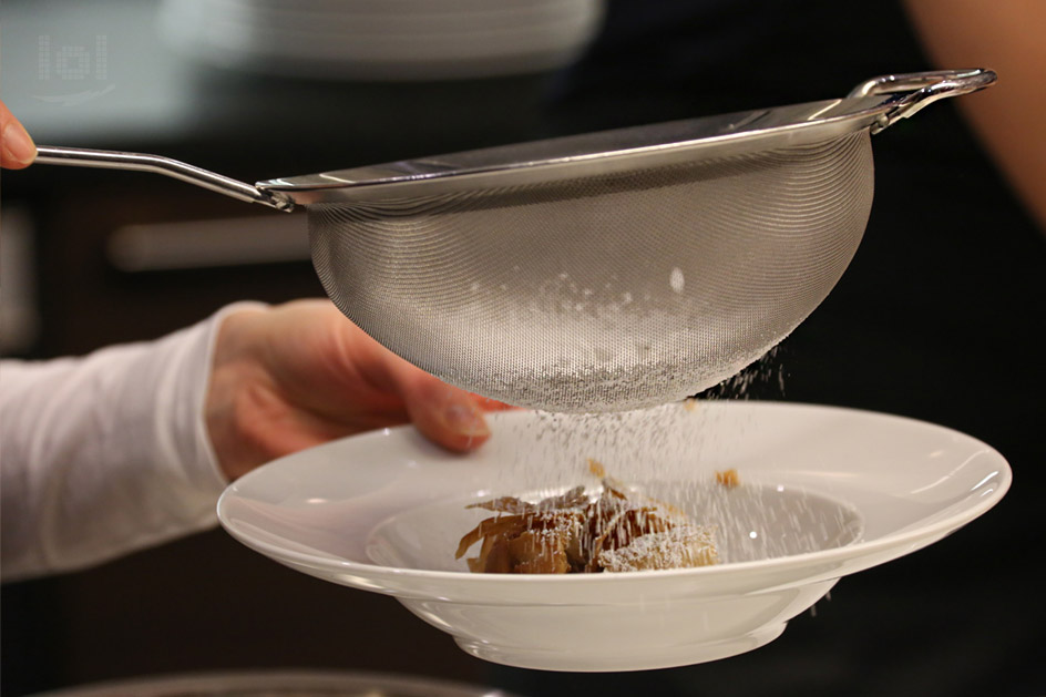 Apfelstrudel mit Puderzucker durch ein Sieb bestäuben