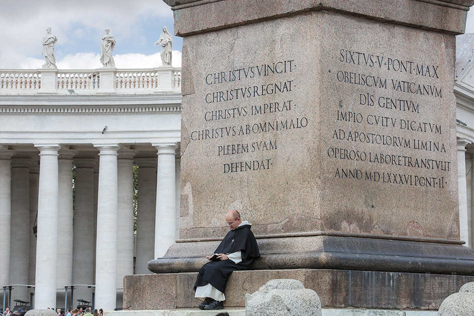 Ein Priester liest in Ruhe mitten auf dem Petersplatz ein Buch