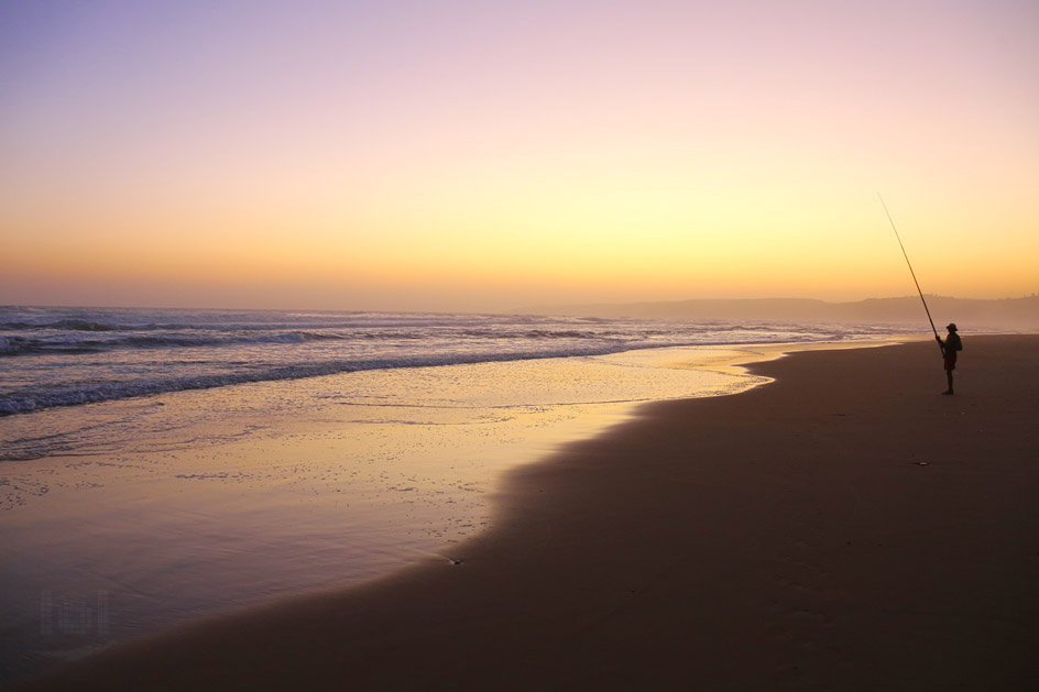 Brandungsangeln am Atlantik im Sonnenuntergang in Südafrika