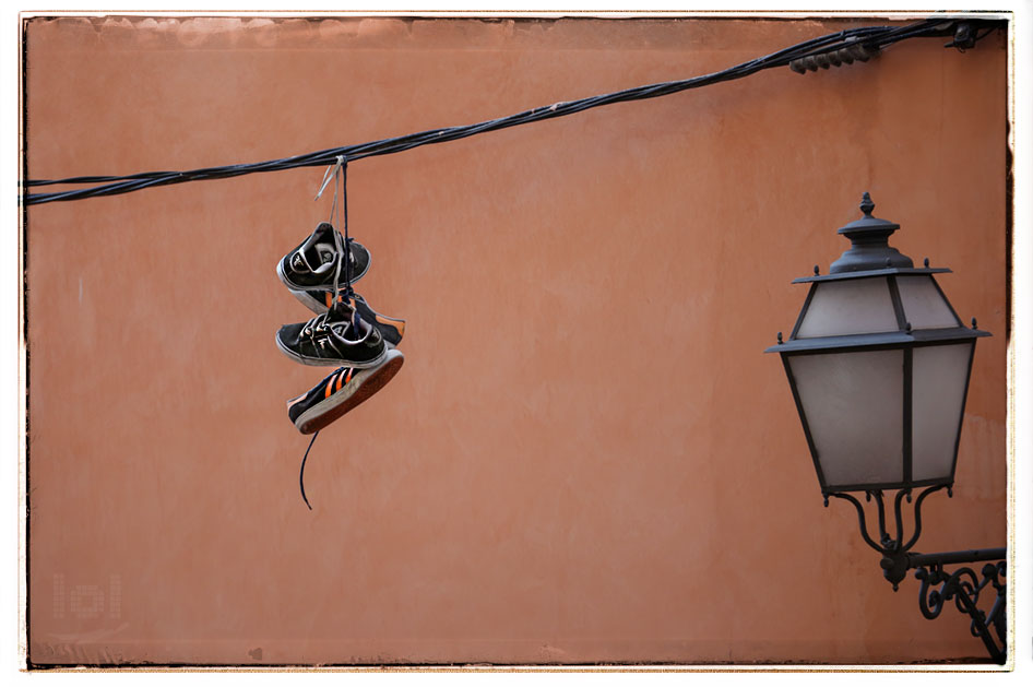 Turnschuhe hängen an einem Kabel vor einem Haus